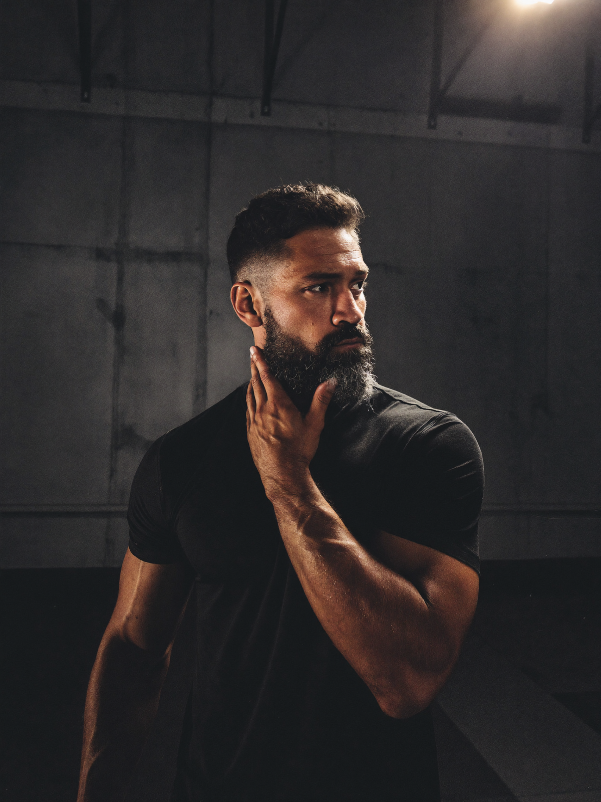 Strong bearded man in a black t-shirt in a dark gym