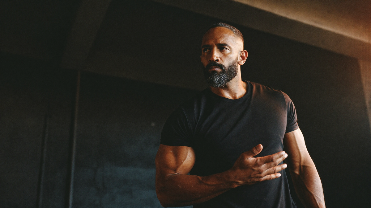 Strong bearded man in a black t-shirt in a dark gym